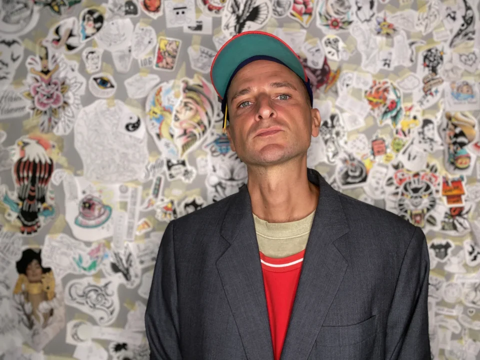Ritratto di Marco, tatuatore di Bunker Tattoo a Monopoli, davanti a una parete di flash tattoo.